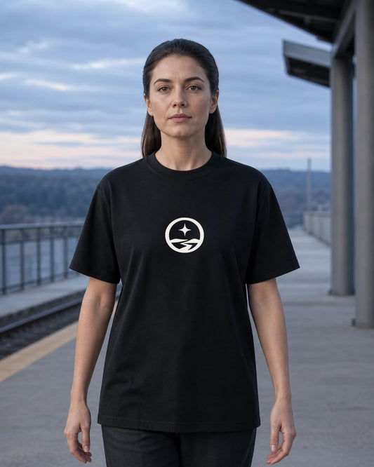 Model outdoors wearing the Somewhere Journey Mark tee in Black, front view